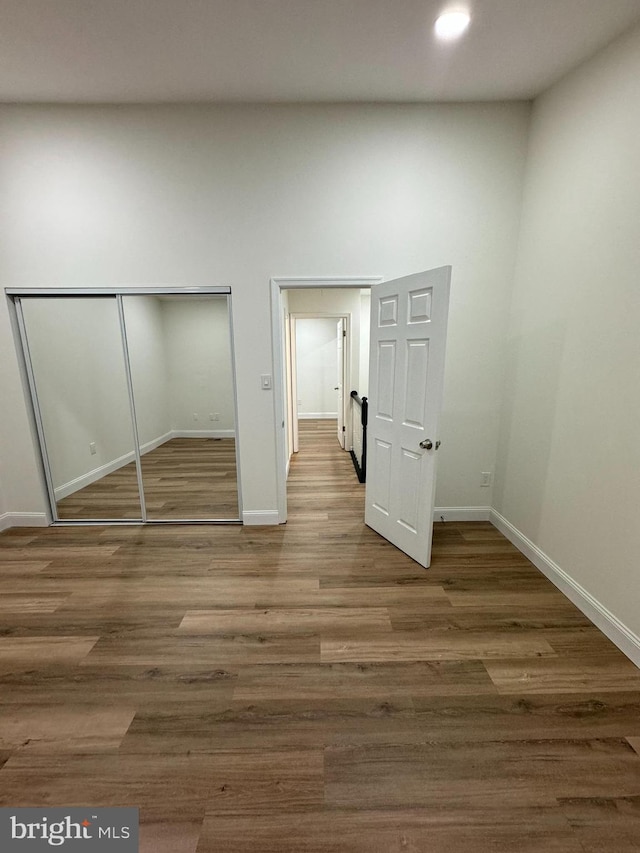 unfurnished bedroom featuring baseboards, a closet, and wood finished floors