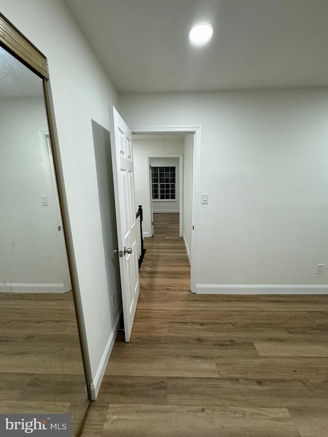 corridor featuring baseboards and wood finished floors