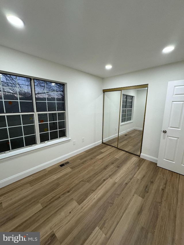 unfurnished bedroom with baseboards, recessed lighting, wood finished floors, and visible vents