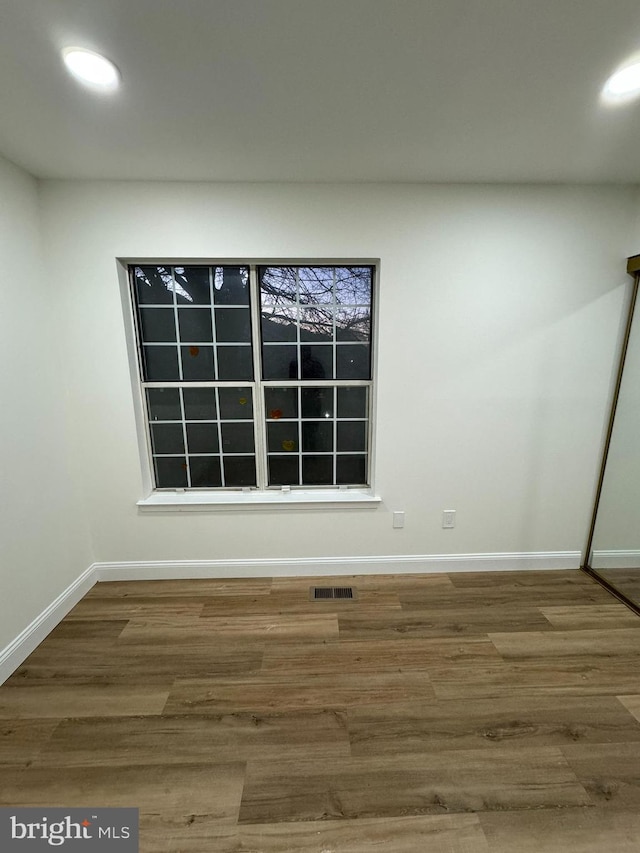 unfurnished room with baseboards, recessed lighting, wood finished floors, and visible vents