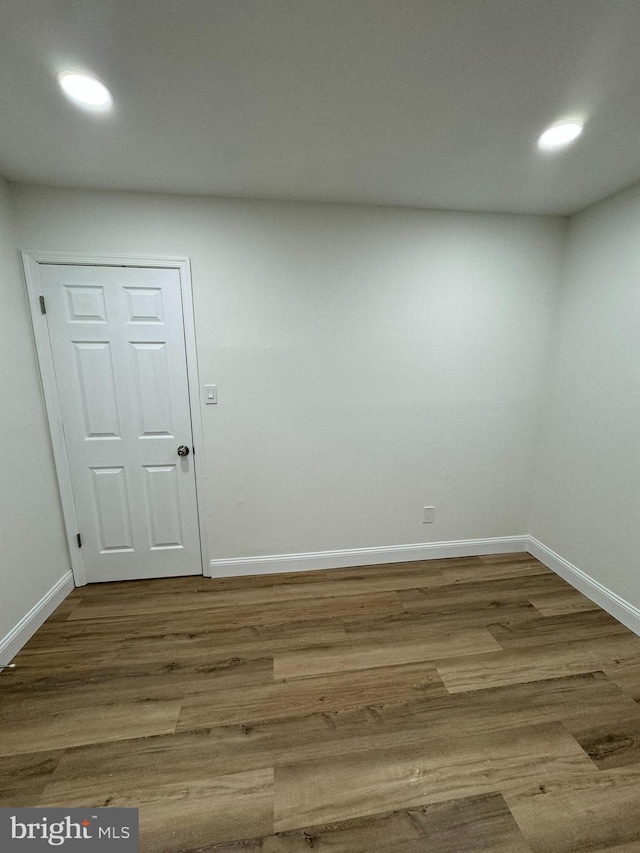 spare room with baseboards, recessed lighting, and wood finished floors