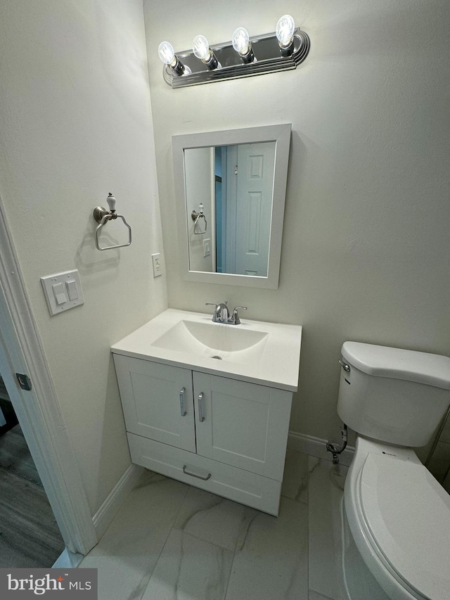 bathroom featuring baseboards, marble finish floor, toilet, and vanity