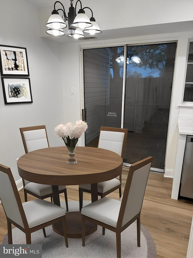 dining room with baseboards, a chandelier, and light wood-style floors