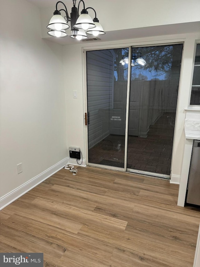 unfurnished dining area featuring baseboards, wood finished floors, and a chandelier