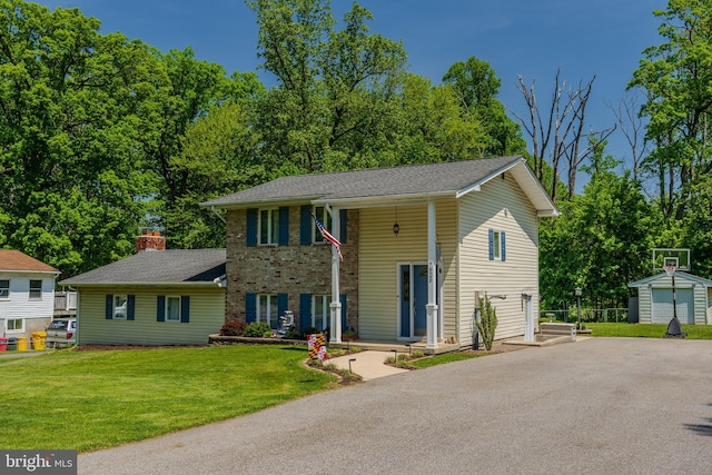 raised ranch featuring brick siding, driveway, an outbuilding, and a front lawn