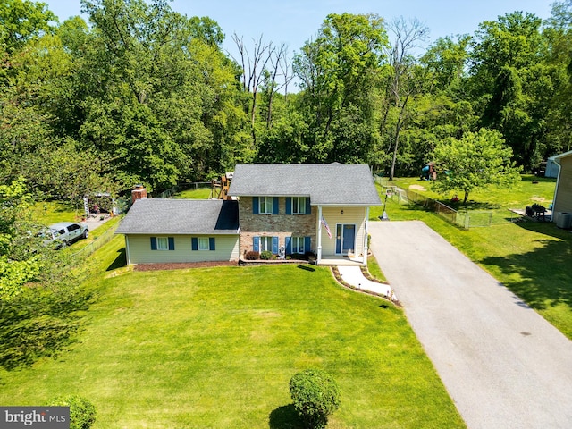 view of front facade featuring fence, a chimney, a front yard, and aphalt driveway
