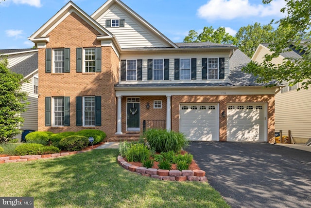view of front of house featuring driveway, brick siding, a front yard, and a garage