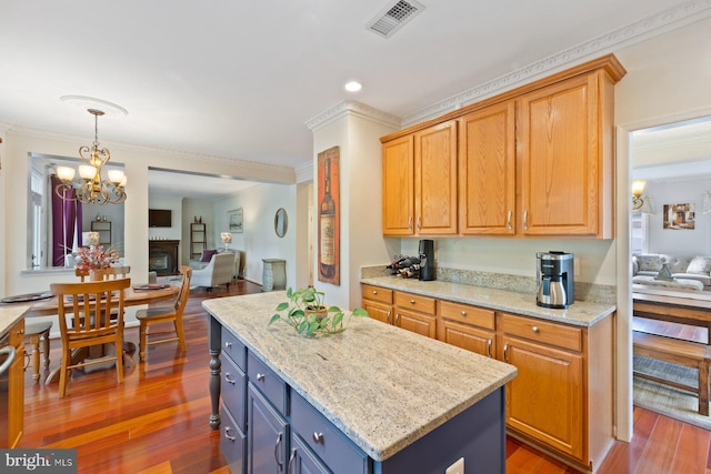 kitchen with a center island, crown molding, wood finished floors, light stone countertops, and open floor plan