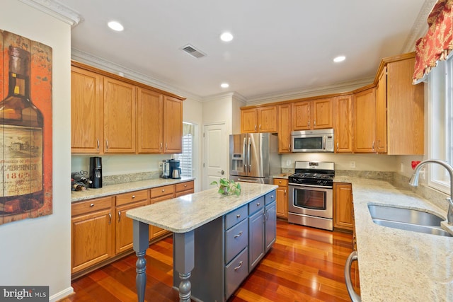 kitchen featuring stainless steel appliances, a sink, crown molding, a kitchen island, and dark wood-style flooring
