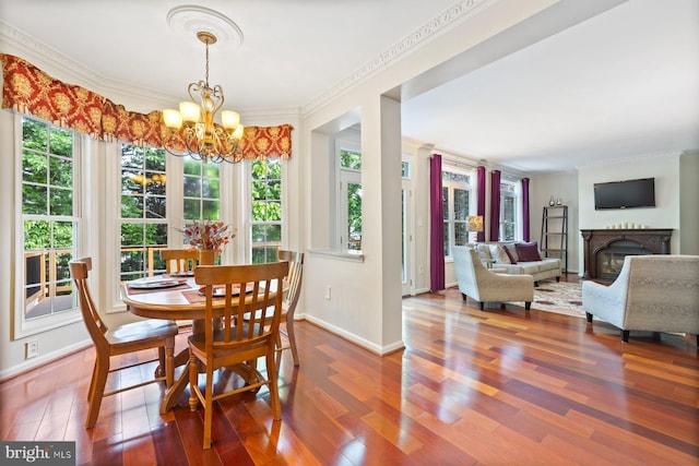 dining room featuring wood finished floors, plenty of natural light, a chandelier, baseboards, and ornamental molding