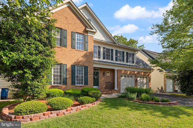 traditional home with a garage, brick siding, driveway, and a front yard