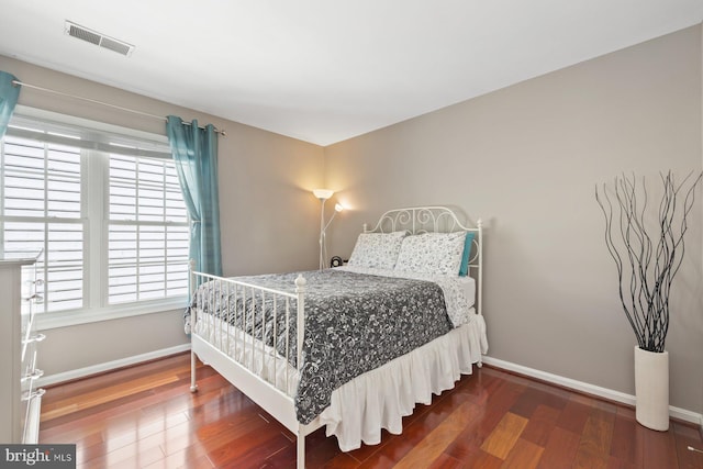 bedroom featuring wood finished floors, multiple windows, and baseboards