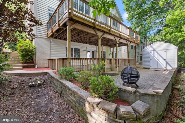 rear view of property featuring a fire pit, a shed, a deck, an outbuilding, and a patio area