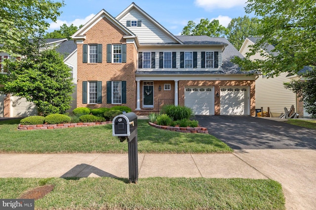 view of front facade featuring driveway, a front yard, brick siding, and an attached garage