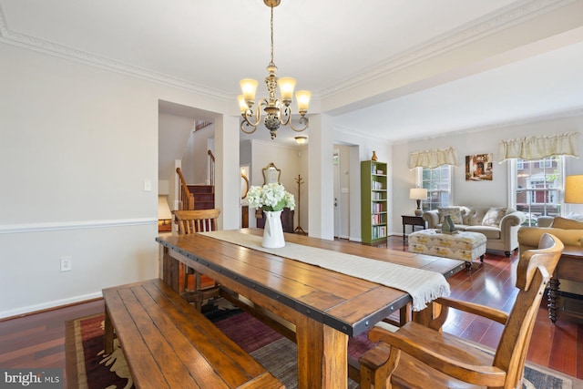 dining space featuring wood-type flooring, a chandelier, crown molding, stairway, and baseboards