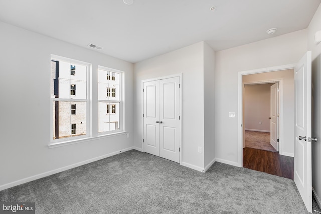 unfurnished bedroom featuring carpet floors, baseboards, visible vents, and a closet