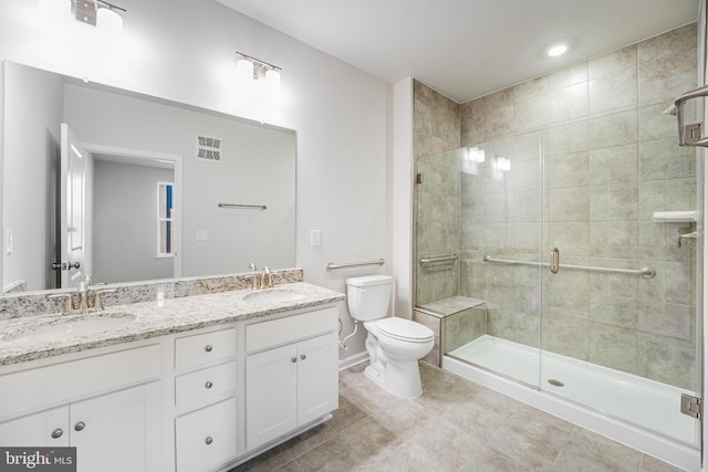 full bathroom featuring double vanity, a sink, a stall shower, and toilet