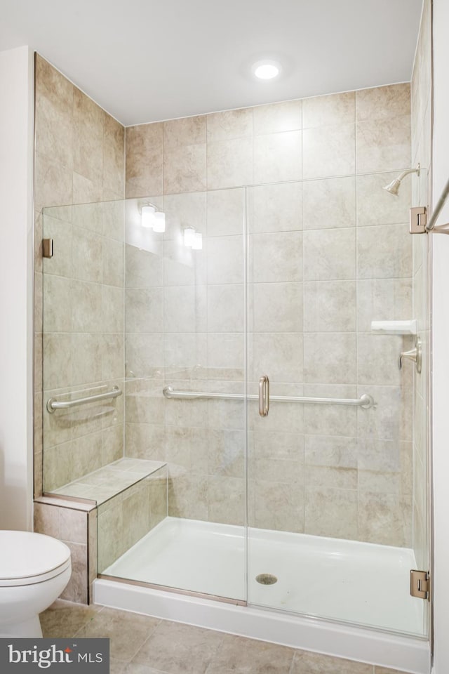 bathroom featuring tile patterned floors, a shower stall, and toilet