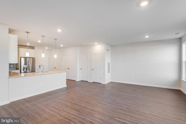 unfurnished living room with visible vents, dark wood finished floors, a sink, baseboards, and recessed lighting