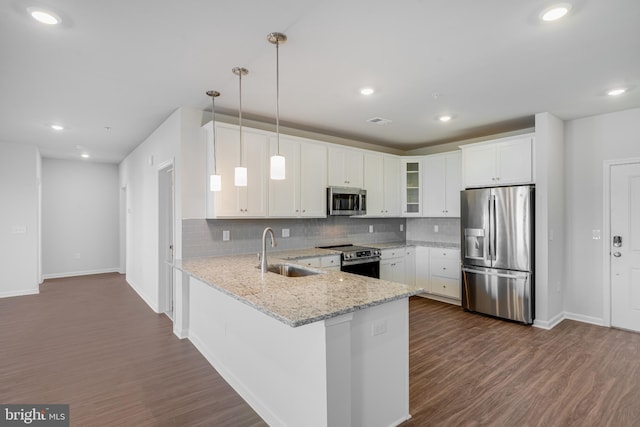 kitchen featuring a sink, stainless steel appliances, baseboards, tasteful backsplash, and glass insert cabinets