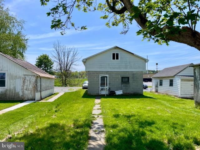 rear view of house featuring a lawn and an outbuilding
