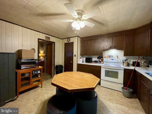 kitchen with light countertops, electric range, a ceiling fan, and dark brown cabinets