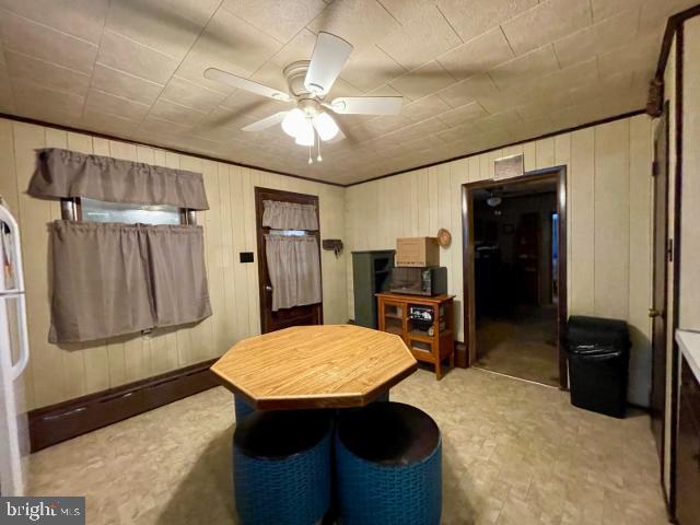 living area with a ceiling fan and wooden walls