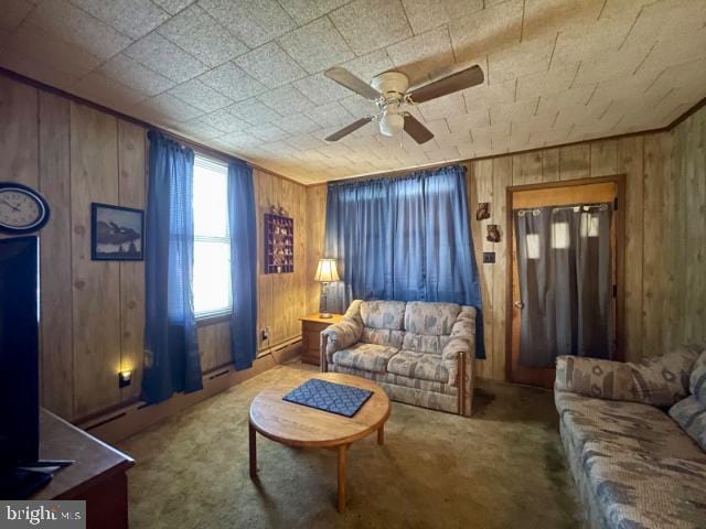 carpeted living area with wood walls, ceiling fan, and a wood stove
