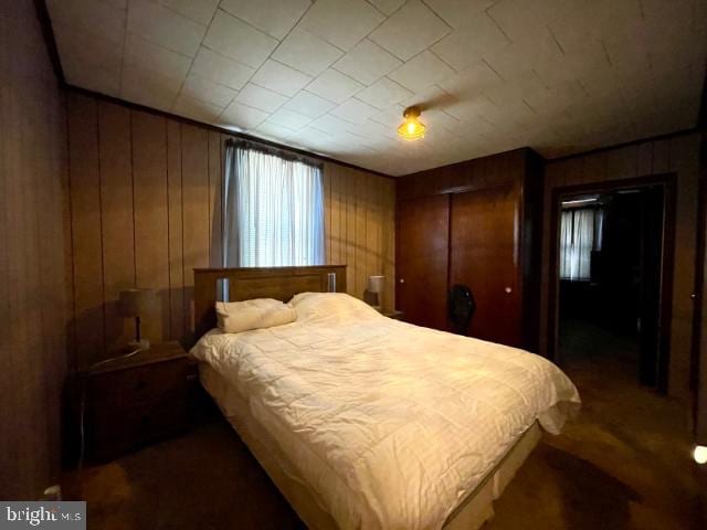 bedroom with a closet and wooden walls