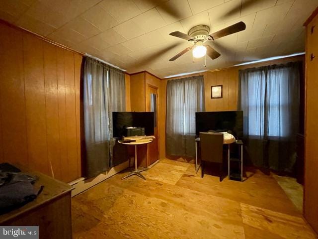 office space featuring light wood finished floors, ceiling fan, and wooden walls