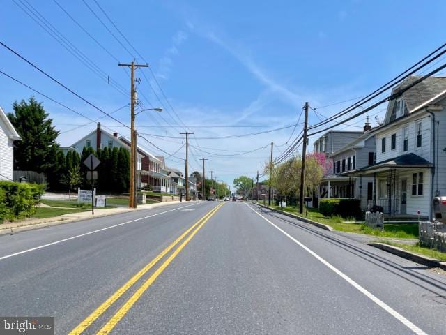 view of road with curbs, street lights, sidewalks, and a residential view