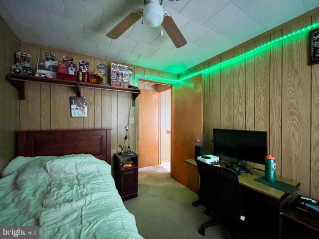 carpeted bedroom with wooden walls and a ceiling fan