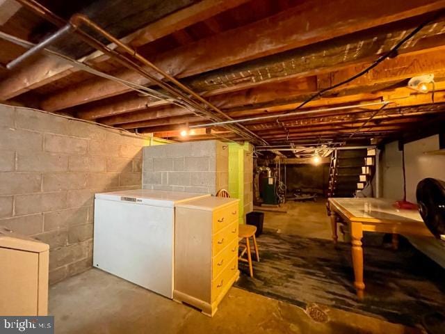 unfinished basement featuring refrigerator