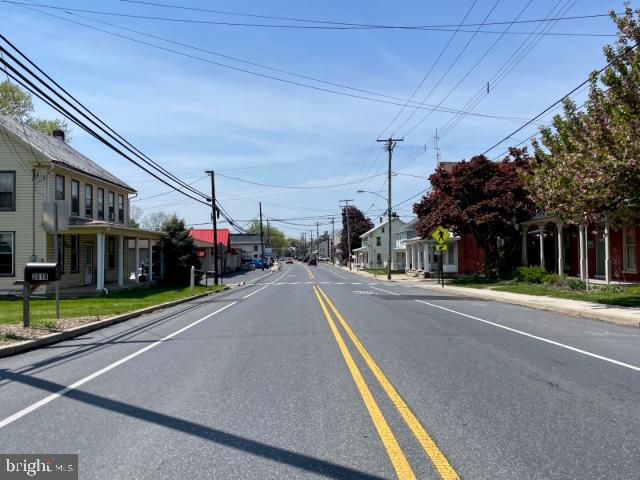 view of road featuring a residential view, sidewalks, curbs, and street lights