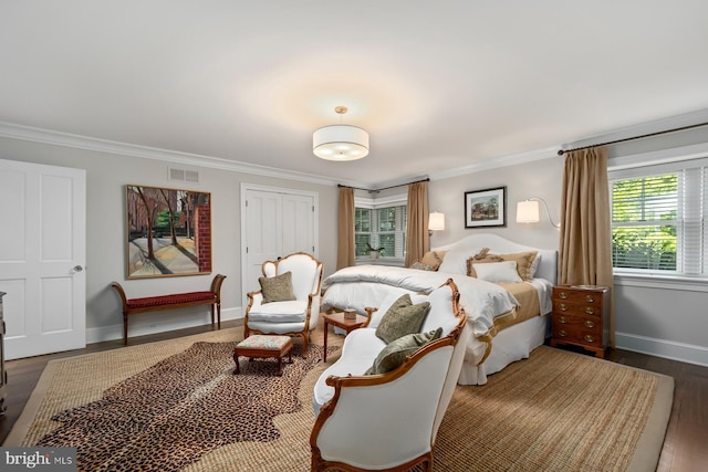 bedroom with ornamental molding, baseboards, wood finished floors, and a closet
