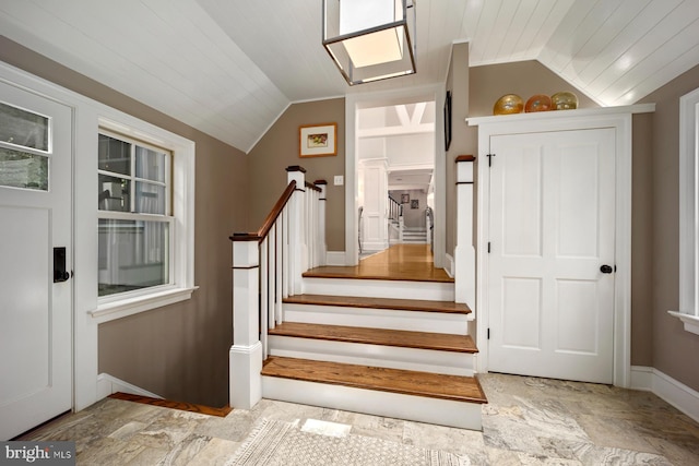 stairs with lofted ceiling, stone finish flooring, and baseboards