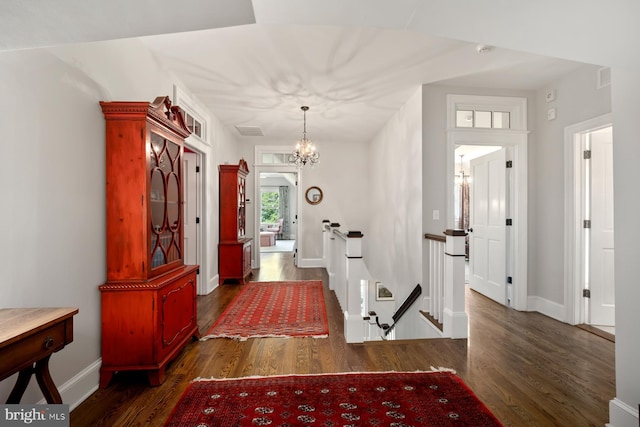 entrance foyer with a chandelier, wood finished floors, and baseboards