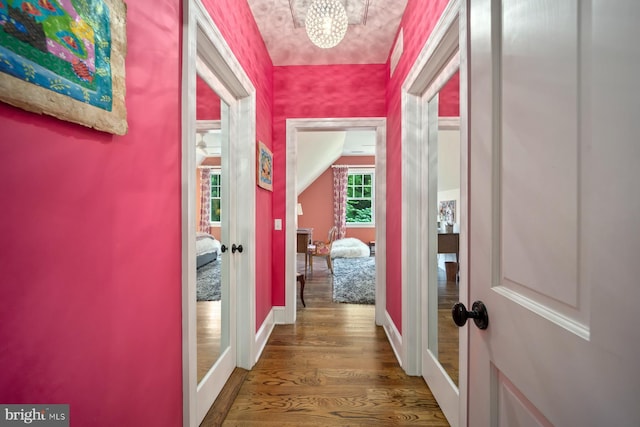 hallway featuring french doors, wood finished floors, vaulted ceiling, baseboards, and a chandelier
