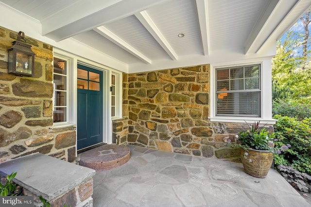 property entrance with stone siding and a porch