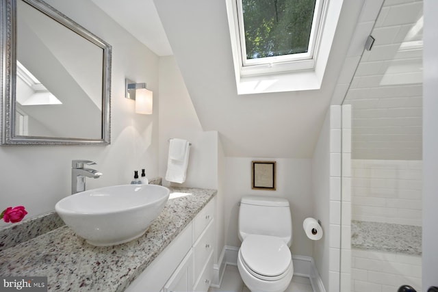 bathroom with a skylight, toilet, vanity, tiled shower, and lofted ceiling