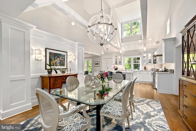 dining area featuring a chandelier, high vaulted ceiling, light wood-type flooring, and beamed ceiling