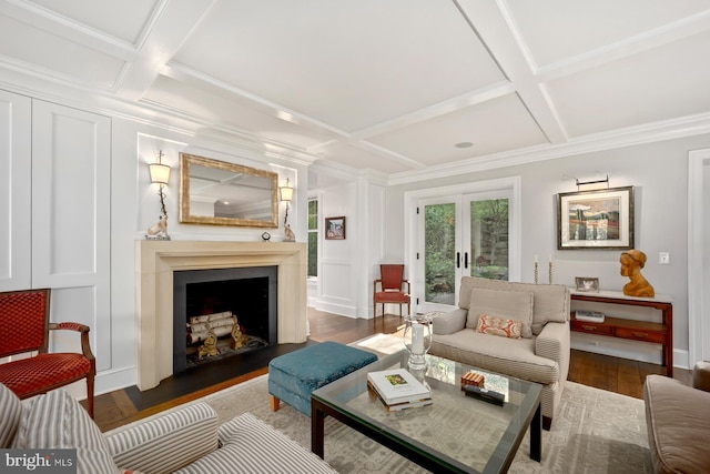 living area featuring coffered ceiling, beamed ceiling, wood finished floors, a large fireplace, and a decorative wall
