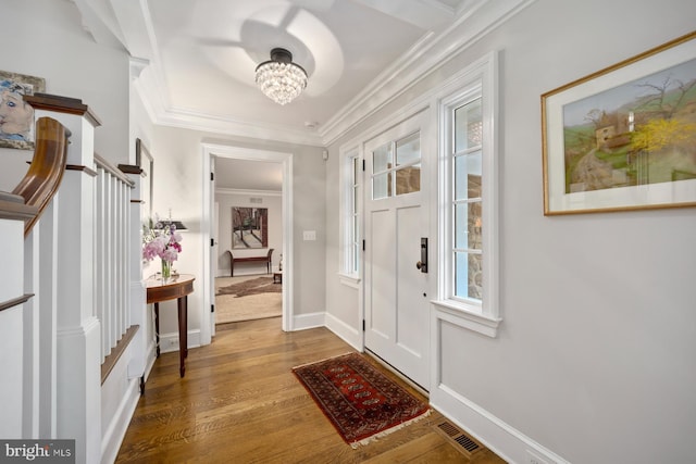 foyer with crown molding, wood finished floors, a chandelier, and baseboards