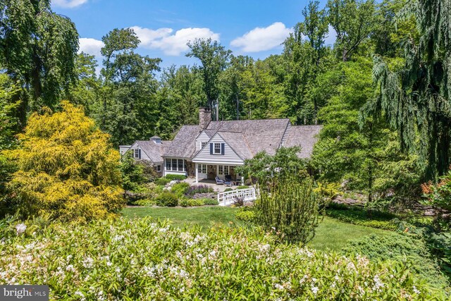 1660 Mount Pleasant Rd, Villanova, PA 19085 - view of front of house with a chimney, a patio, and a forest view