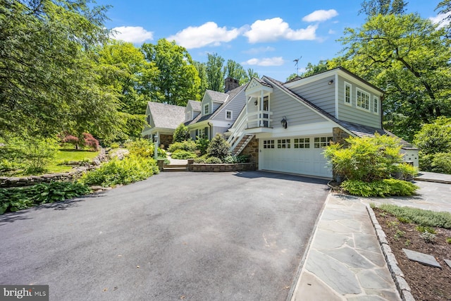 1660 Mount Pleasant Rd, Villanova, PA 19085 - view of front facade featuring a chimney, a garage, stone siding, stairway, and aphalt driveway