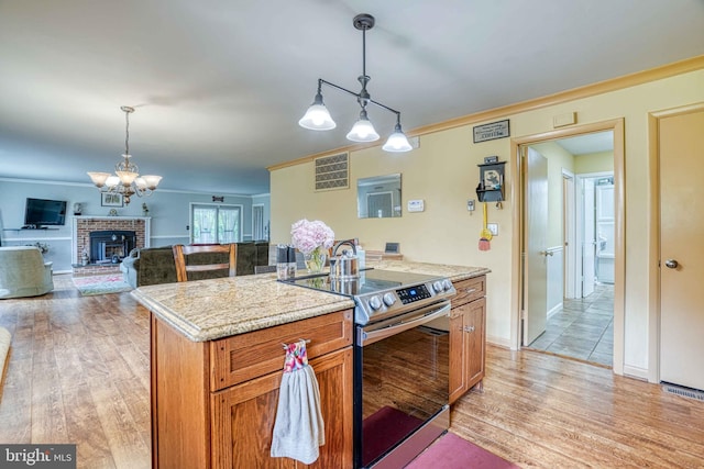 14957 Cherry Ln, Ridgely, MD 21660 - kitchen featuring stainless steel electric range, hanging light fixtures, light wood-type flooring, crown molding, and a brick fireplace