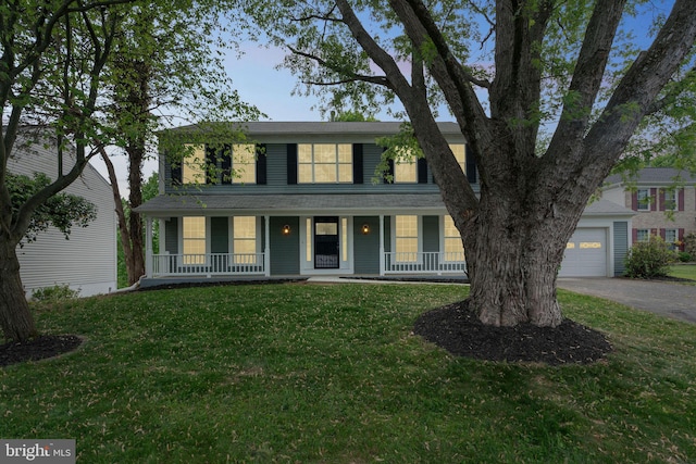 view of front facade featuring covered porch, an attached garage, driveway, and a front yard