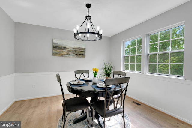 dining area featuring visible vents, baseboards, a notable chandelier, and light wood finished floors