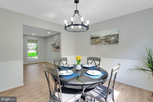 dining area with baseboards, light wood finished floors, and a chandelier