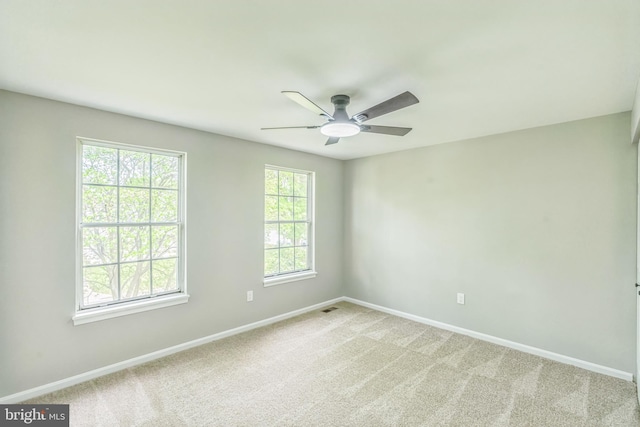 empty room featuring baseboards, visible vents, light carpet, and ceiling fan